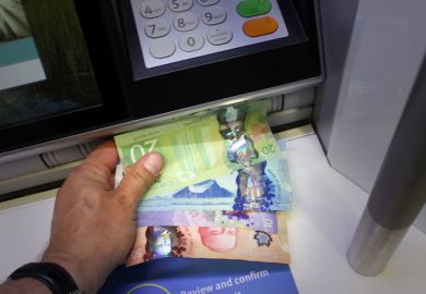 Someone takes Canadian money from an ATM