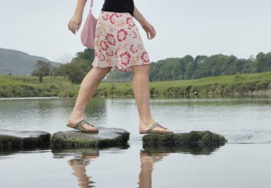 Career progression, woman walking across stepping stones in water Career progression, woman walking across stepping stones in water