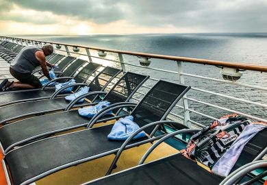 A man puts a towel on a lounger on the deck of a ship A man puts a towel on a lounger on the deck of a ship