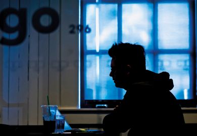 silhouette of anonymous student sitting at laptop