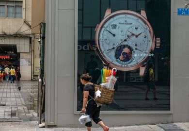 A local woman carries a bamboo basket, walking past a luxury watch shop at Jiefangbei CBD, Chongqing, 2015 