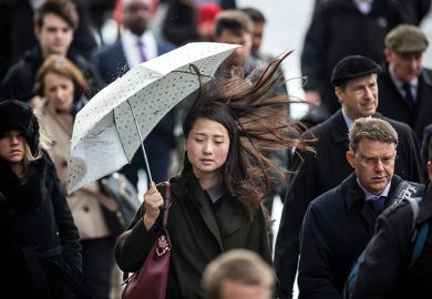 Asian woman holding umbrella on windy day