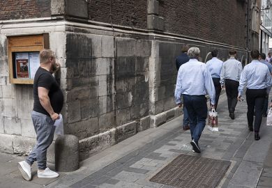A man watching workers walk away from him in London. To illustrate that graduates can be better off than those without degrees.
