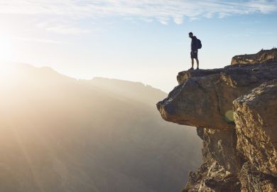 A man looks over the edge of a cliff, illustrating the drop-off in ERC funder in mid-career