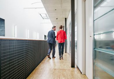 Older man and woman in university corridor, illustrating staff-student relationships. Older man and woman in university corridor, illustrating staff-student relationships.