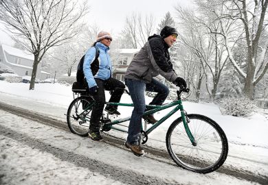 Couple riding tandem bike in the snow