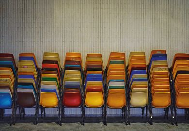 Colourful set of chairs piled up by a wall
