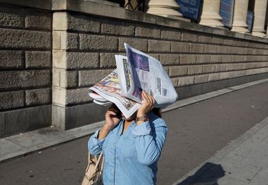 Woman covers her face with paper