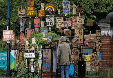 A member of the public walks past a display of signs relating to Covid A member of the public walks past a display of signs relating to Covid