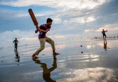 Boys play cricket on the beach