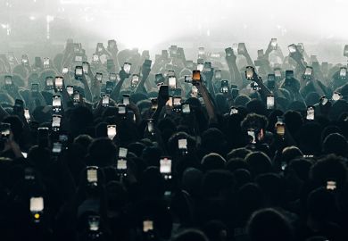 A crowd holding up mobile phones. To illustrate ‘near universal’ AI use leading to ‘polarisation’ among students.