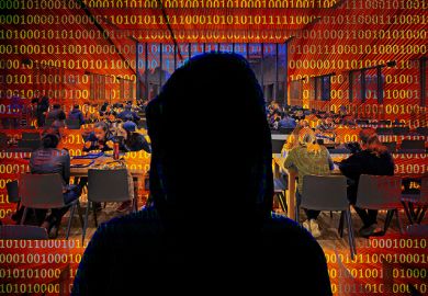 Silhouette portrait of a cyber hacker, with students from the University of Nottingham in the background.