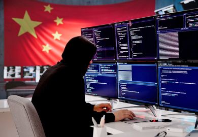 Cybersecurity expert coding with Chinese flag displayed In background. To illustrate that universities have been told by MI5 to review their ties with a Chinese research institute after spy warning.