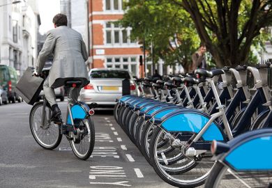 Man in suit rides Boris bike (Santander cycle) in London