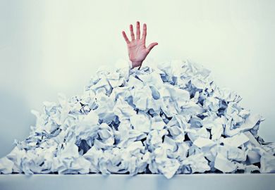 Hand sticking out of a mound of crumpled paper