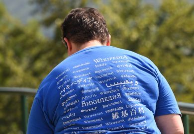 A man attending the Wikimania meeting, wears a shirt reading "Wikipedia" in different languages.