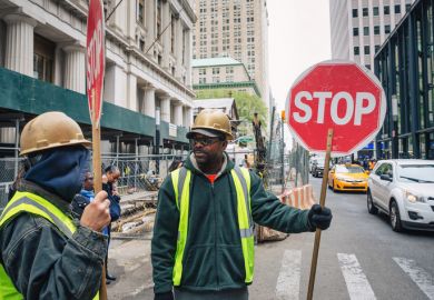 A minority ethnic man with a sign to stop traffic A minority ethnic man with a sign to stop traffic