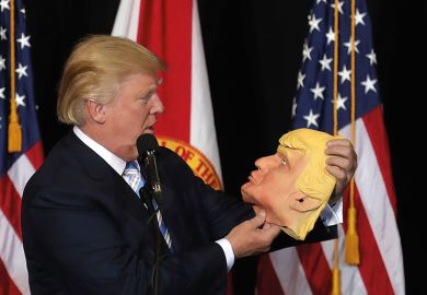 Donald Trump holding mask of his own face