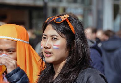 A young Asian woman has the Dutch flag painted on her cheek