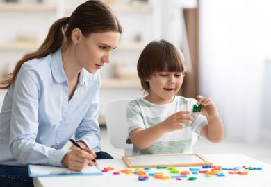 A woman with a clipboard observes a child A woman with a clipboard observes a child