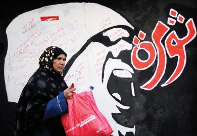 Egyptian woman walks past 'Revolution' graffiti, American University in Cairo Egyptian woman walks past 'Revolution' graffiti, American University in Cairo