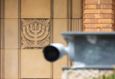 A Menorah engraved in sandstone on the Emanuel Synagogue on Ocean Street, Woollahra in the eastern suburbs of Sydney. In the foreground is a security camer