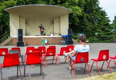 One person with empty seats watching a guitarist on stage, illustrating that the number of international students enrolling in the English higher education sector has fallen by more than a tenth this year