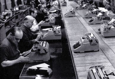 Men typing in a row in a factory