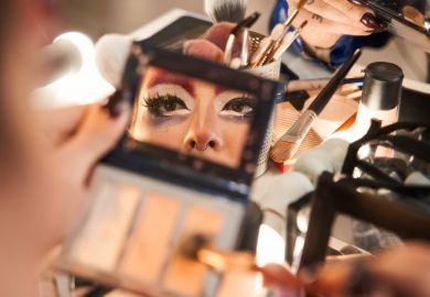 A drag queen applies make-up looking in a hand-mirror Face of drag queen