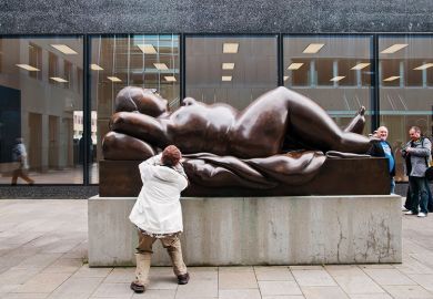 A tourist takes pictures of a sculpture of a voluptuous naked woman in Vaduz, Liechtenstein