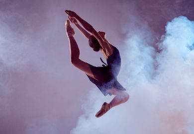 Female ballet dancer jumping through dry ice