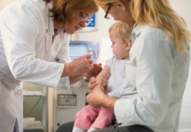 Female doctor administering vaccine to small child Female doctor administering vaccine to small child