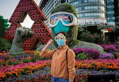 A woman poses in front of a flower display dedicated to healthcare workers during the Covid-19 pandemic