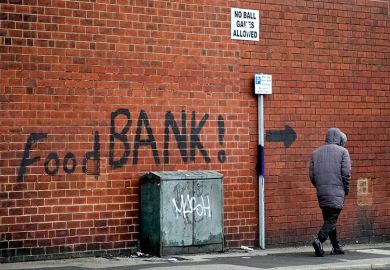 A sign painted on the side of a house directs people to a local food bank in Leeds, England. To illustrate the cost-of-living pressures that affect postgraduate researchers.