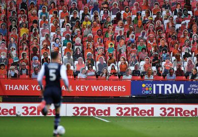 Cardboard cutout fans during football match Soccer player in front of carcboard cutout crowd. Shows diverse supporters to relate to subject diversity improving globally.