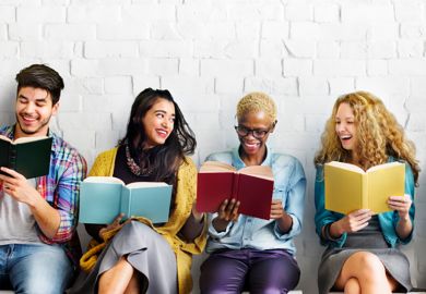 Four people sitting in a row reading books