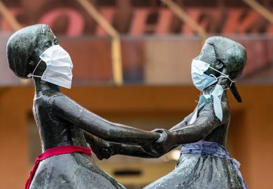 The two female heads of a bronze figure wear a protective face mask on April 3, 2020 in Jena, Germany