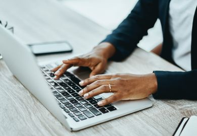 An unrecognisable person using a laptop in an office 