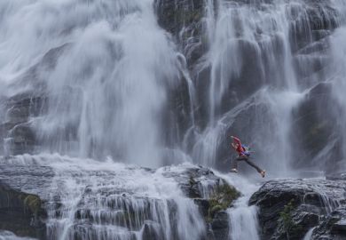  climber jumping between rocks under the "Cascata del Toce" (Toce waterfall), a waterfall in the Italian Alps