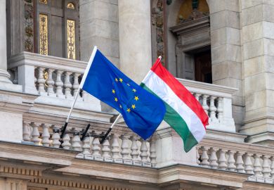 Flags of the European Union and Hungary flying from poles outside an ornate building in the centre of  Budapest