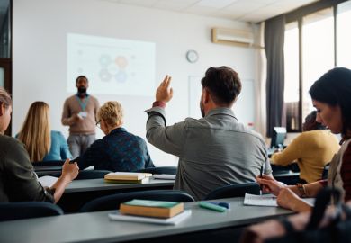 A man raises his hand in a classroom 
