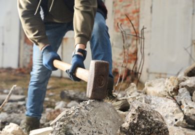 Man breaking stones with sledgehammer outdoors