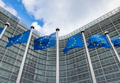 European flags waving in the wind side by side in front of the Berlaymont building facade, headquarters of the European Commission.