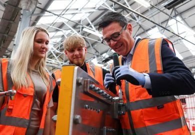 Britain's Prime Minister Andy Burnham uses a ratchet spanner, as he visits French run rail transport systems manufacturer Alstom in Derby
