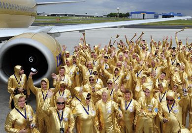 People in gold outfits next to a plane People in gold outfits next to a plane