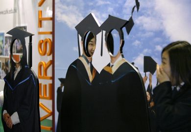 Visitors to a careers expo peek through a cardboard cut out of graduates. To illustrate 'fake' students which can be pushed by recruitment agents.