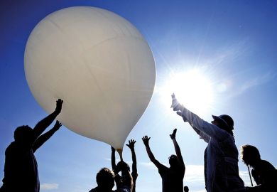 Group of people push balloon into the air