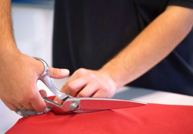 Hand cutting red cloth with scissors Hand cutting red cloth with scissors