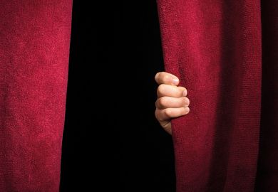 A hand on a theatre curtain