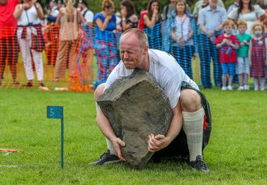 Man struggling to lift a stone at the Highland Games in Dundonald, Scotland. To illustrate a shortfall in funding for Scottish universities. Man struggling to lift a stone at the Highland Games in Dundonald, Scotland. To illustrate a shortfall in funding for Scottish universities.